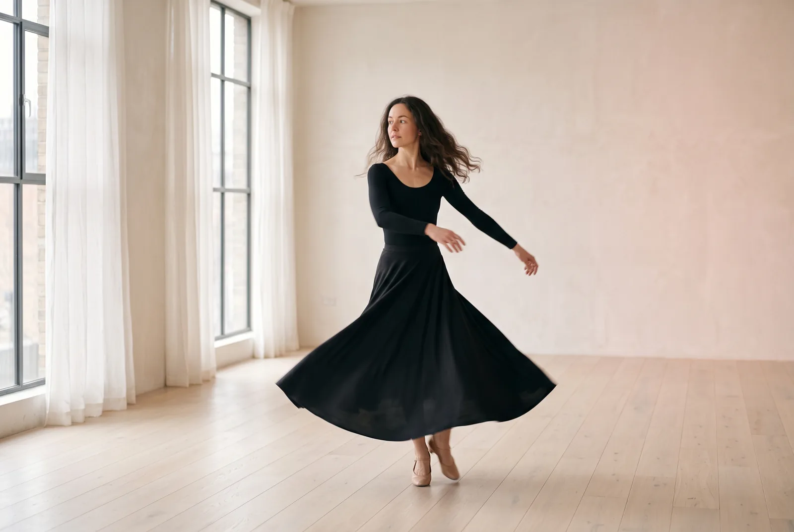 A dancer mid-turn, her long skirt flowing, in a bright studio.